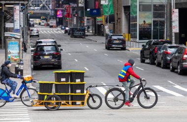 Manhattan, New York, ABD - 5 Nisan 2020 Coronavirus salgını sırasında 6. Cadde 'de bisiklet teslimatçısı. Amazon paketlerini teslim etmek için kullanılan bisiklet römorku.