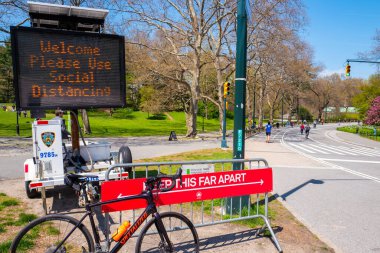 Central Park, New York, ABD - 19 Nisan 2020: New York Şehri Parkları ve NYPD New York 'taki koronavirüs salgınının durdurulması sırasında sosyal mesafeyi gösteren bir tabela gösteriyor.