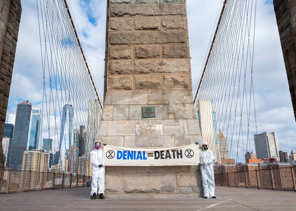 New York, New York, ABD - 25 Nisan 2020: 2 erkek, kişisel koruyucu ekipman-PPE, inkar eşittir New York 'taki Brooklyn Köprüsü' nün tepesinde, covid-19 salgınıyla ilgili ölüm pankartı taşıyorlar..