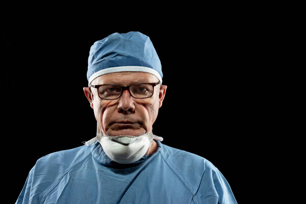 Fatigued Healthcare Worker. portrait of a Doctor working long hours during the coronavirus pandemic; photographed against black background