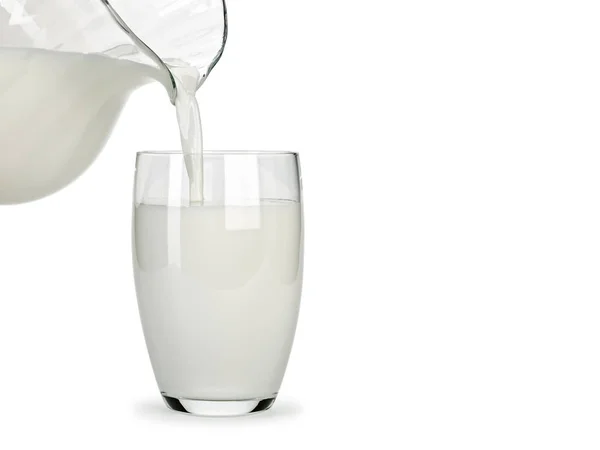 Наполнение стакана молоком из стеклянного кувшина — стоковое фото