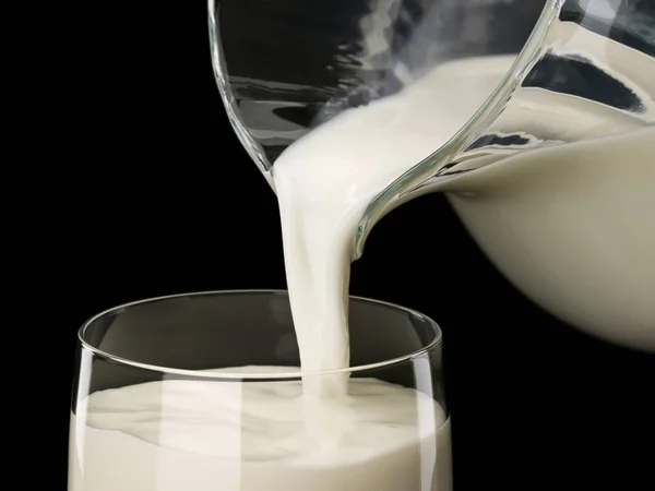 Enchimento de um copo por leite de um jarro de vidro — Fotografia de Stock