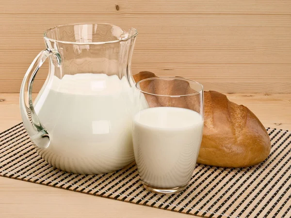 Üvegáruk töltött tejet és egy hosszú fehér kenyér-kenyér — Stock Fotó