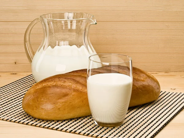 Посуда, наполненная молоком и буханкой белого цвета — стоковое фото