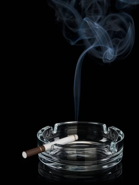 Sigara dumanı, cam kül tablasında koyu filtre ile siyah üzerinde izole edilir.