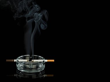 İki sigaranın dumanı, koyu ve açık renkli filtresi cam kül tablasında, siyah üzerine izole edilmiştir.