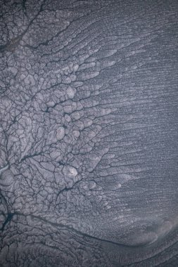 Dramatik siyah, tek renkli soyutlama, ejderha pullarını ya da kek lavlarını anımsatıyor, koyu gri, gümüş ve bronz aksanlarla parıldıyor. Alkolik mürekkep birbirine karışıyor. Modern bir sanat eserinin parçası..