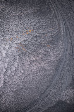 Dramatik siyah, tek renkli soyutlama, ejderha pullarını ya da kek lavlarını anımsatıyor, koyu gri, gümüş ve bronz aksanlarla parıldıyor. Alkolik mürekkep birbirine karışıyor. Modern bir sanat eserinin parçası..