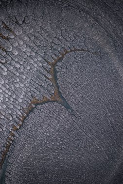 Dramatik siyah, tek renkli soyutlama, ejderha pullarını ya da kek lavlarını anımsatıyor, koyu gri, gümüş ve bronz aksanlarla parıldıyor. Alkolik mürekkep birbirine karışıyor. Modern bir sanat eserinin parçası..