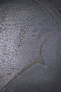 Dramatik siyah, tek renkli soyutlama, ejderha pullarını ya da kek lavlarını anımsatıyor, koyu gri, gümüş ve bronz aksanlarla parıldıyor. Alkolik mürekkep birbirine karışıyor. Modern bir sanat eserinin parçası..