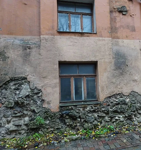 Old city house building architecture with window above damaged concrete stone wall and pawing stones