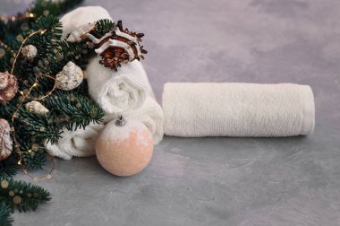 Noel ve Yeni Yıl Spa konsepti. Gri arka planda ışık, kabuk, taş ve banyo bombasıyla süslenmiş köknar dalları.