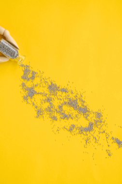 Sarı arka planda bir kavanoz gümüş konfeti tutan elleri olan şenlikli moda konsepti.