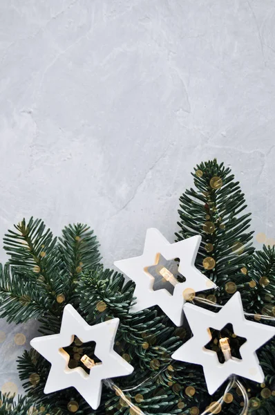 Magisch kerstthema: gezellige, warme lichtjes, bloemenslinger, sterren en dennentakken op de grijze achtergrond. — Stockfoto