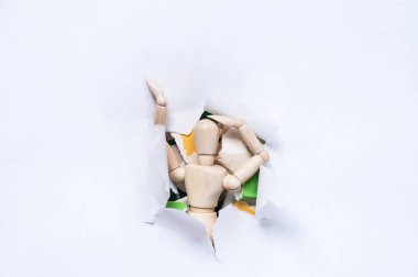 Tahta bir adam ve bir kağıt parçası ve karton yırtık beyaz bir kağıttan dışarı bakar..