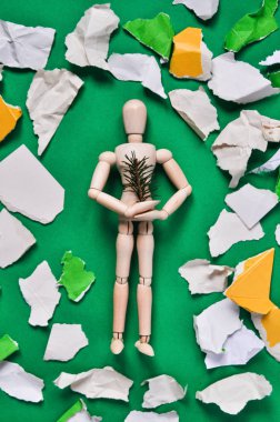 Atık kağıt ve kartonla çevrili köknar dalı olan ahşaptan yapılmış bir adam modeli..