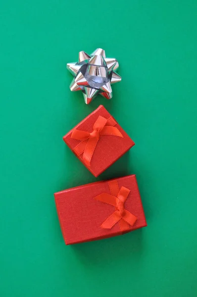 Dois presentes vermelhos e uma estrela de prata estão na forma de uma árvore de Natal. Conceito criativo — Fotografia de Stock