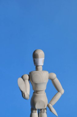 Tahtadan yapılmış, tıbbi maskeli bir adam ellerini kaldırıp tehlike uyarısı yapıyor. Koronavirüs, salgın ve salgın konsepti