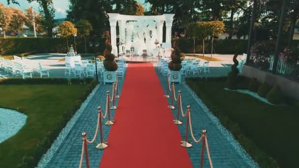 Luchtfoto op prachtige bruiloft ceremonie setup met witte arche en rode loper. — Stockvideo