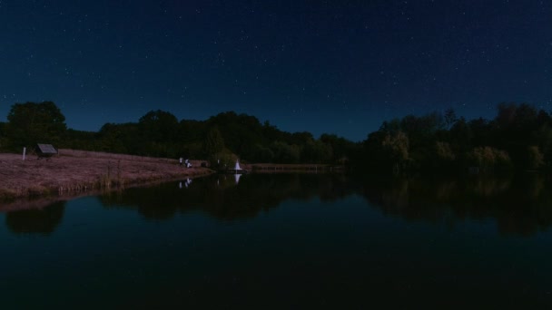 Incrível vista noturna do lago com brilho estrelas reflexão na água e feliz noiva romântica e noivo no fundo . — Vídeo de Stock