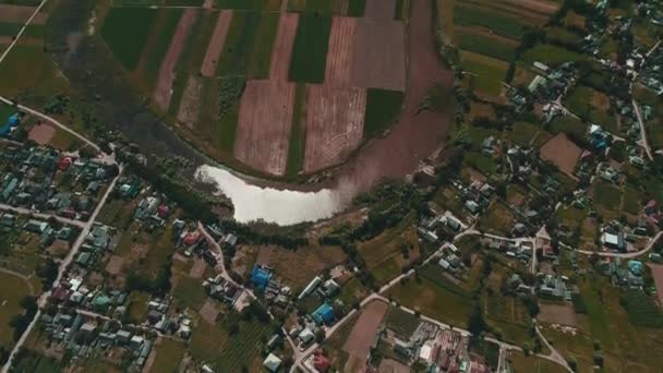 Lucht uitzicht op het prachtige landschap met groot dorp, dan uitzicht op een rivier serpentine en weelderige groene weiden. — Stockvideo