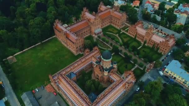 Coloridos edificios antiguos de la Universidad de Chernivtsi con torres y cúpulas y jardín verde con pasarelas en el fondo del cielo en Ucrania . — Vídeo de stock