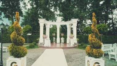 Güzel yeşil park bölgesinde beyaz kemer ve halı ile kurulmuş güzel düğün töreninin tersten görüntüsü..