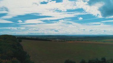 Agricultural field furrows in countryside from above and cloudy blue sky.