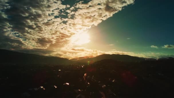 Vuelo de gran altitud por encima del paisaje poblado con cordillera de siluetas brumosas en el horizonte y vista al atardecer con nubes esponjosas . — Vídeos de Stock