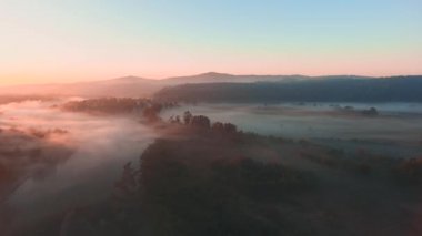 Scenic flight through the thick fog lying on fields and forests towards the sun.