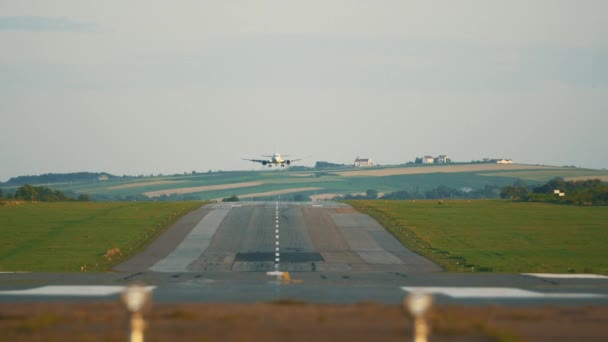 Um vídeo frontal de uma pista de pouso do aeroporto com um avião, descendo, pousando e andando em direção à câmera . — Vídeo de Stock