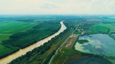 Yeşil kırsal bölgedeki demiryolu yakınlarında sel ve kirli nehirlerin üzerinden uçmak..