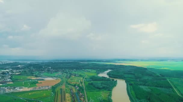 Vista aérea de las tierras de cultivo con pequeño pueblo y el río en el fondo de las montañas . — Vídeo de stock