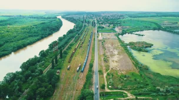Ovanifrån på många järnvägsspår och tåg som rör sig längs en flod på landsbygden. — Stockvideo