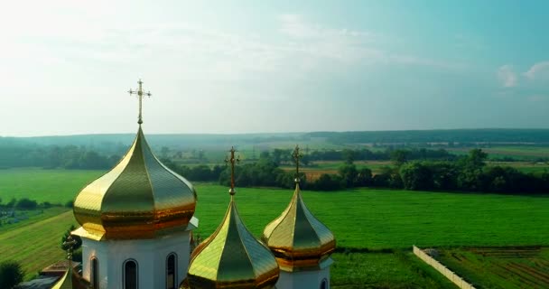 전원 지역의 청명 한 하늘을 배경으로 황금색 돔 과 정교회 성당을 가로지르는 십자가. — 비디오