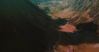 Güneşli bir sonbahar gününde yeşil uçurumlar ve vadiler boyunca dağın zirvesine giden yol..