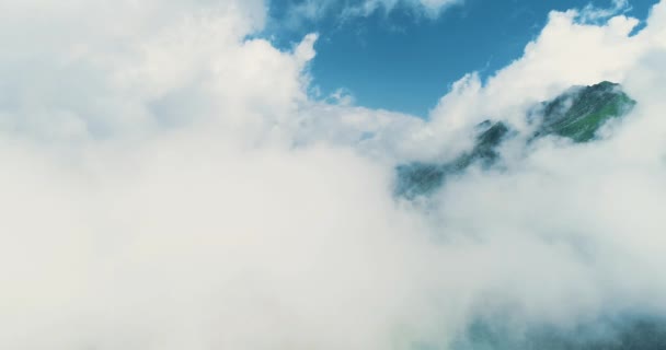 Дрон летить високо в блакитному небі через пухнасті хмари над загадковими горами на сонячному світлі . — стокове відео