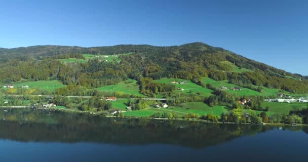 Pueblo valle verde en colinas verdes en el fondo de las montañas, cerca del lago . — Vídeos de Stock