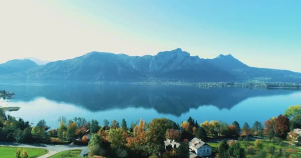 Letecký dron s výhledem na majestátní hory a letovisko na břehu čistého jezera. — Stock video