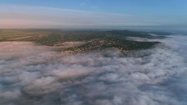 Güneşin doğuşunda sisle kaplı tepelerde büyük bir yerleşim olan aereal manzaranın ileri hareketi.