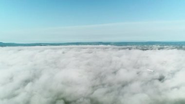 Bulutlardan mavi gökyüzüne uçan uçak.