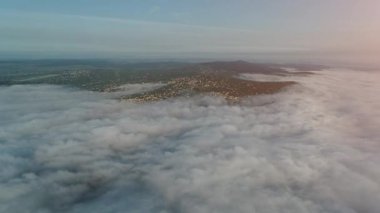 Güneşin doğuşunda sisle kaplı tepelerde büyük bir yerleşim olan aereal manzaranın ileri hareketi.