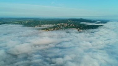 Güneşin doğuşunda sisle kaplı tepelerde büyük bir yerleşim olan aereal manzaranın ileri hareketi.