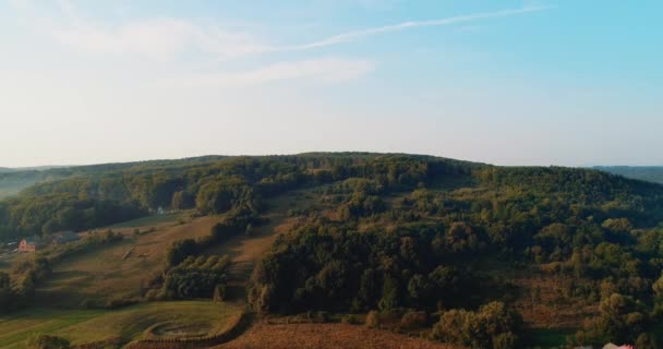 Zonnestralen stralen klein dorp en dichte groene bos heuvels. — Stockvideo