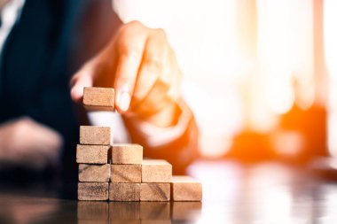 İş dünyasında plan ve strateji. Risk kavramı. İnsanın eli ahşap bir bloğu yığıp istifliyor..