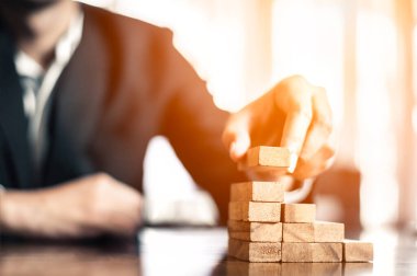 İş dünyasında plan ve strateji. Risk kavramı. İnsanın eli ahşap bir bloğu yığıp istifliyor..