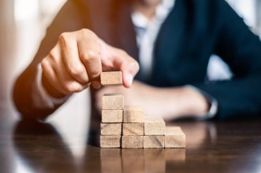 İş dünyasında plan ve strateji. Risk kavramı. İnsanın eli ahşap bir bloğu yığıp istifliyor..