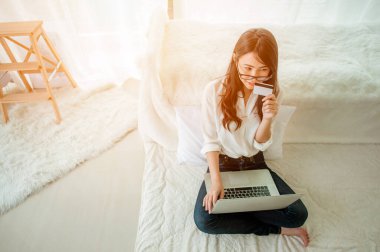 Kredi kartı tutan ve internetten alışveriş yapan bir kadın..