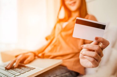 Kredi kartı tutan ve dizüstü bilgisayar kullanan eller. İnternetten alışveriş