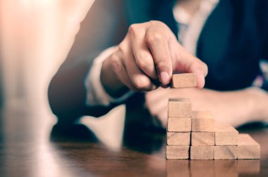 İş dünyasında plan ve strateji. Risk kavramı. İnsanın eli ahşap bir bloğu yığıp istifliyor..